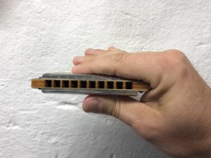 left handed harmonica player holding with right hand